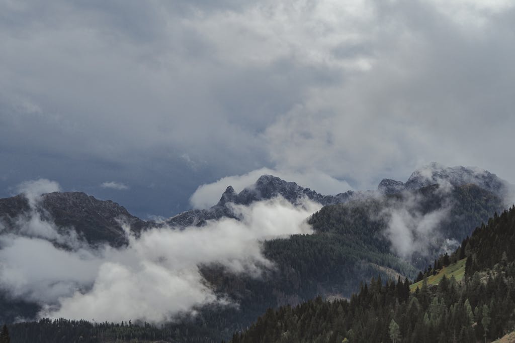A breathtaking view of misty mountains and dense forests under dramatic skies.