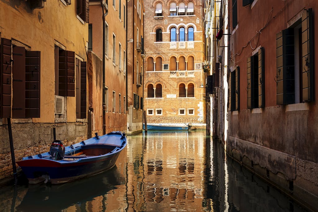 A picturesque Venetian canal scene with colorful boats and historic architecture bathed in sunlight.