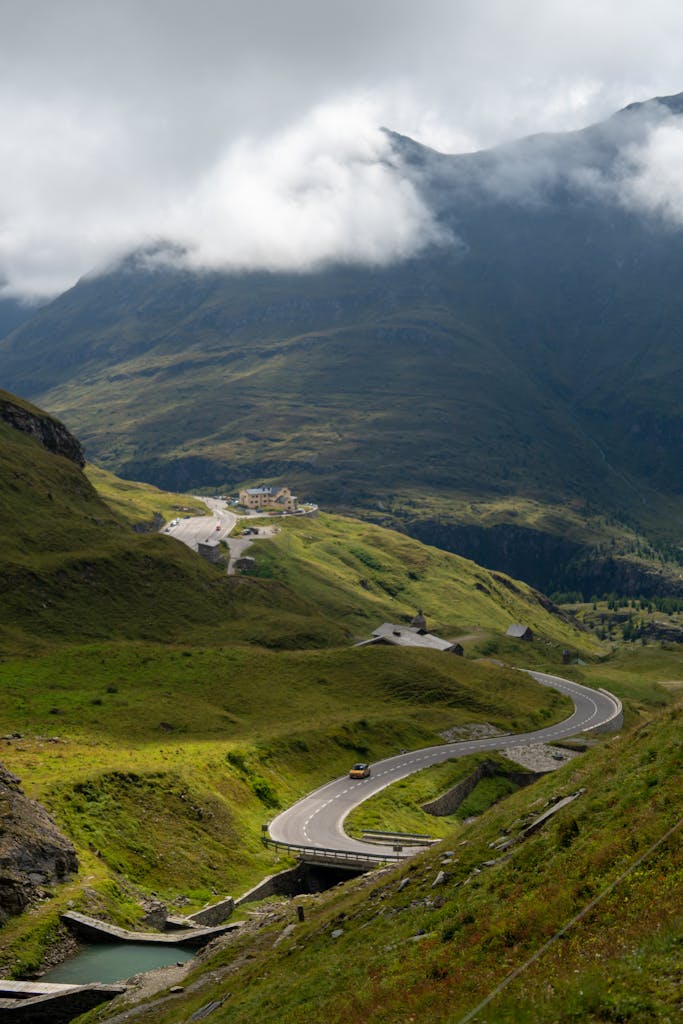 A winding mountain road in the scenic Austrian Alps under dramatic clouds.