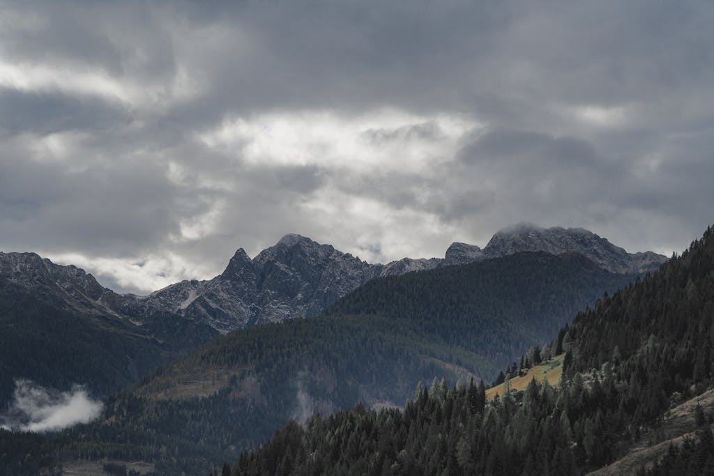 Breathtaking mountain range with dense forest and dramatic clouds.