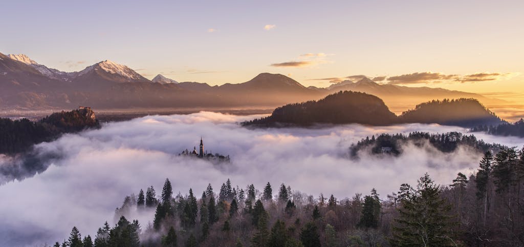 Majestic sunrise over misty mountains and forest, creating a serene landscape.
